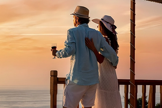 Couple Enjoying Sunset on Balcony Overlooking Ocean, Embracing Romantic Getaway