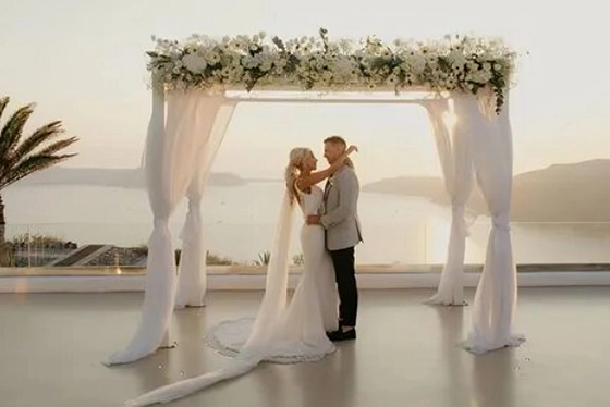 Bride and Groom Under Floral Arch at Sunset Ceremony
