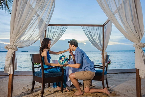 Couple Enjoying Romantic Beach Dinner Under Canopy at Sunset