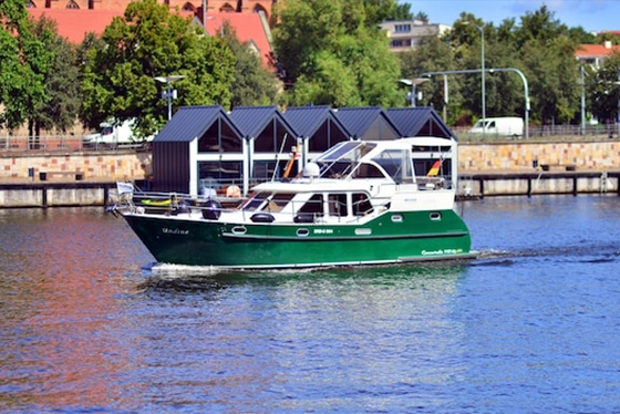 Green Riverboat Cruising Along a Tree-Lined Ohio Riverbank