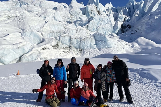 Group of Tourists in Winter Gear Posing on Snowy Landscape