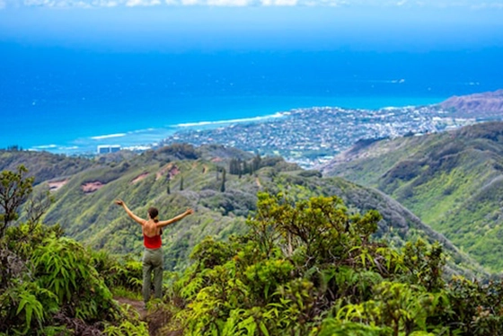 Hiker Enjoys Scenic View of Lush Mountains Overlooking Ocean in Hawaii